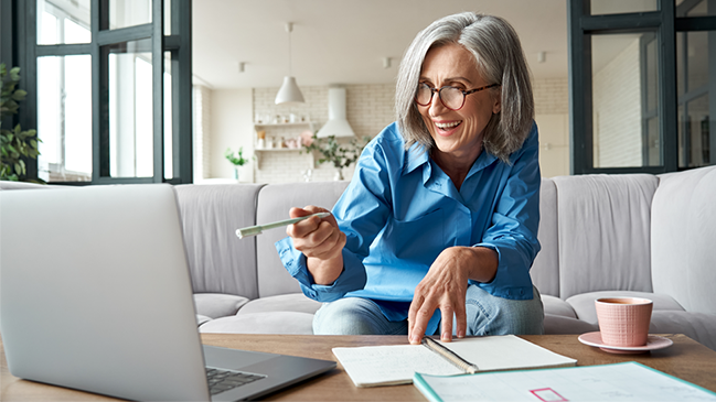 verweist auf: Informationen zur Antragstellung Grauhaarige Frau glücklick am Laptop (verweist auf: Informationen zur Antragstellung)
